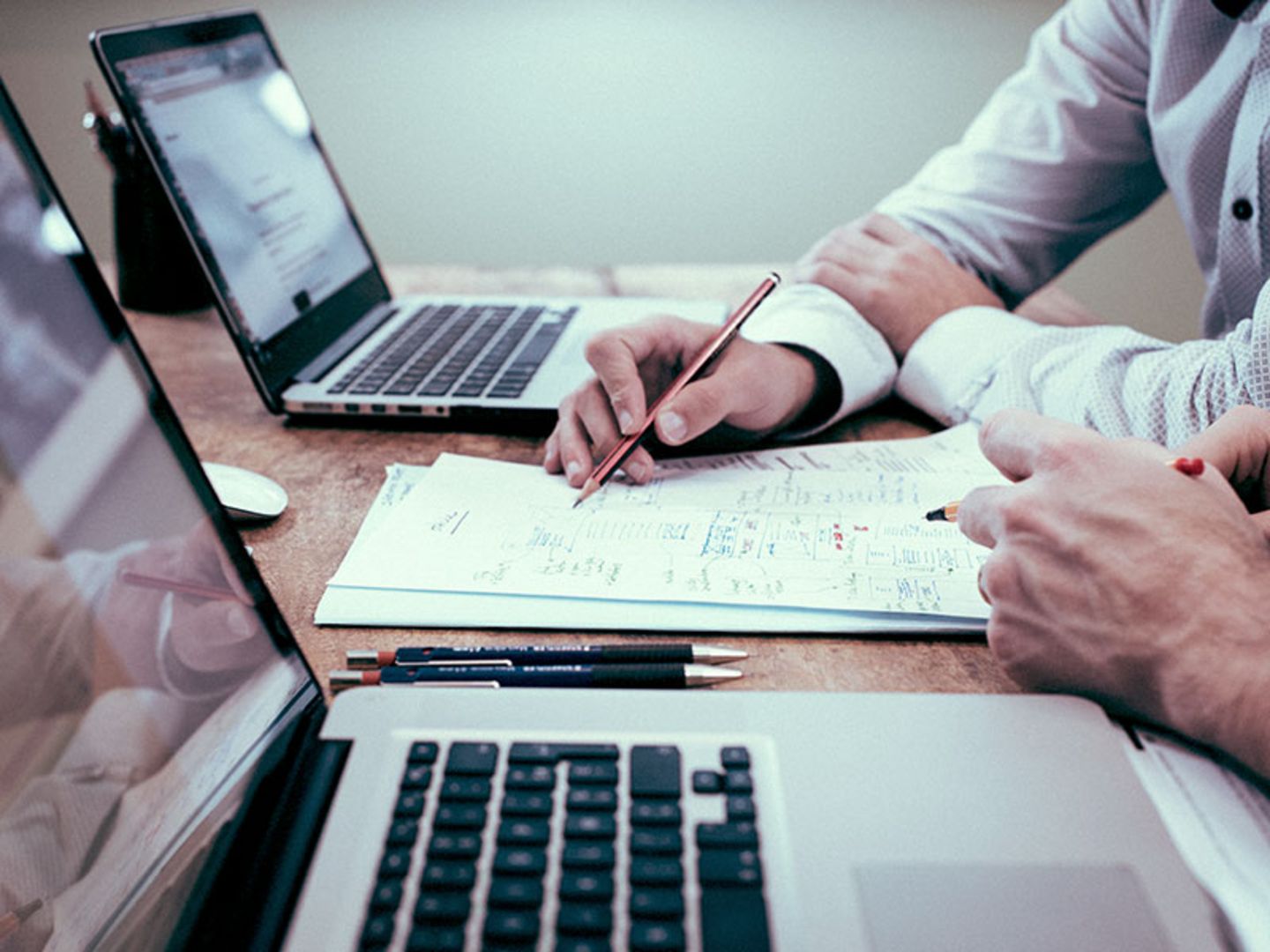 Zwei Personen arbeiten an einem Laptop und Papier